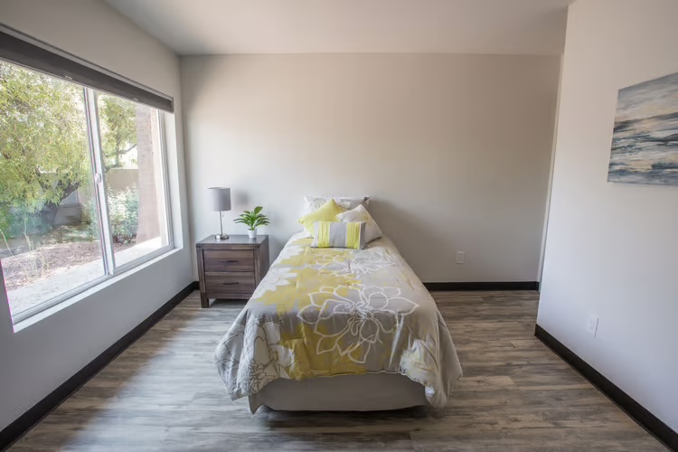 Bright resident bedroom with wood-look floors at McCormick Ranch Assisted Living